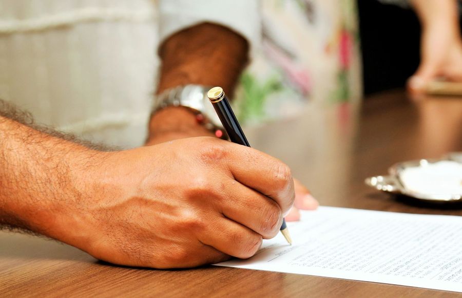 A hand signing a property contract at the table